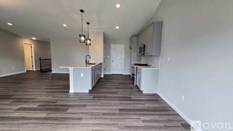 A spacious kitchen with white cabinets and a wooden floor.