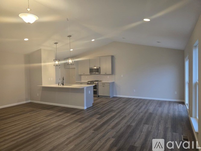 A spacious kitchen and living room with wood flooring and white walls.