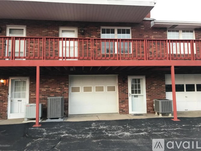 A red building with a balcony and two garage doors.