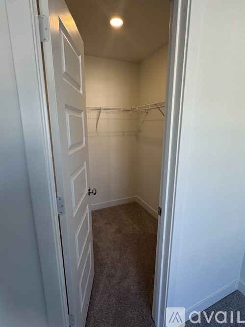 A small, empty room with a door on the left and a closet with a coat rack on the right.