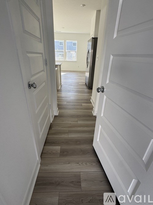 A long hallway with white doors and wood floors.