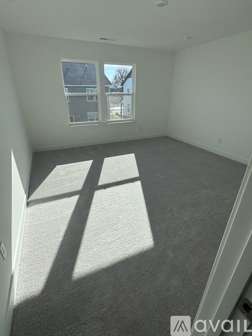 A room with a carpeted floor and a window letting in sunlight.