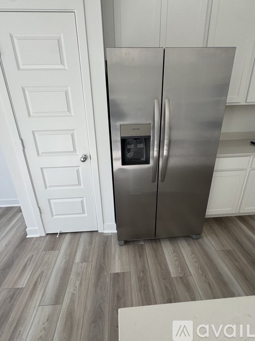 A stainless steel refrigerator with a water dispenser in the middle of the door.