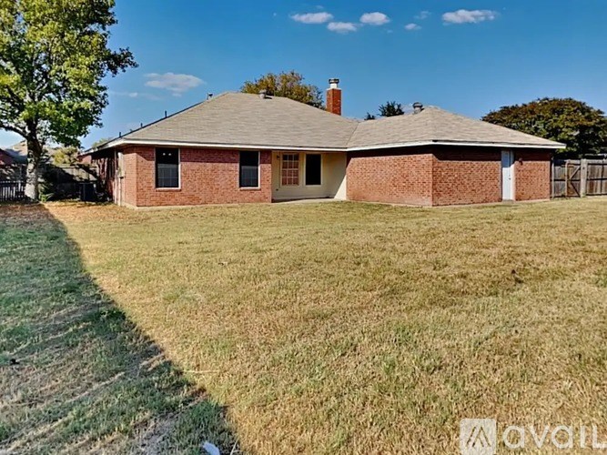 A house with a brown roof and a white door is surrounded by a grassy area.