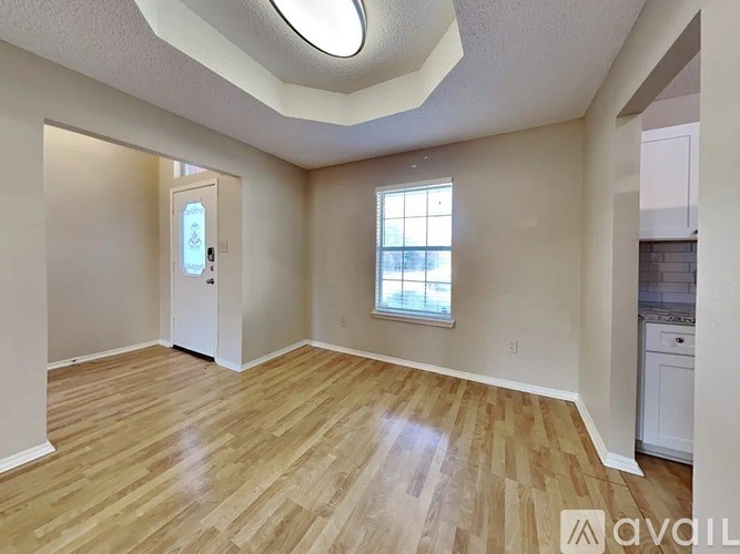 A room with wooden flooring and a window with a white door.