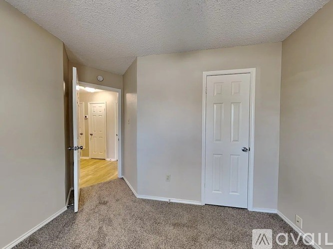 A room with a carpeted floor and two doors, one of which is open.