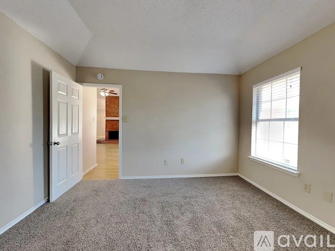 A room with a carpeted floor, a door, and a window.