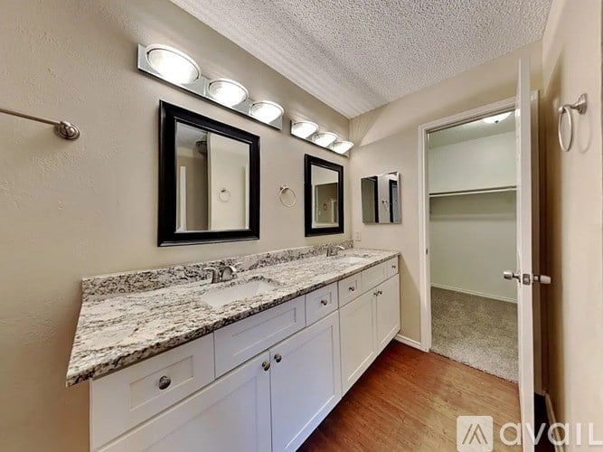 A bathroom with a marble countertop and white cabinets.