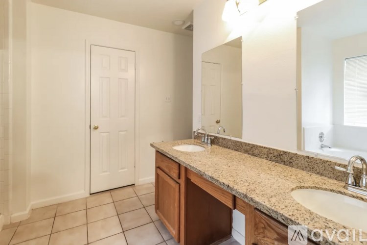 A bathroom with a sink, mirror, and a door.