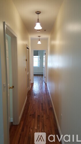 A hallway with wood floors and white walls.