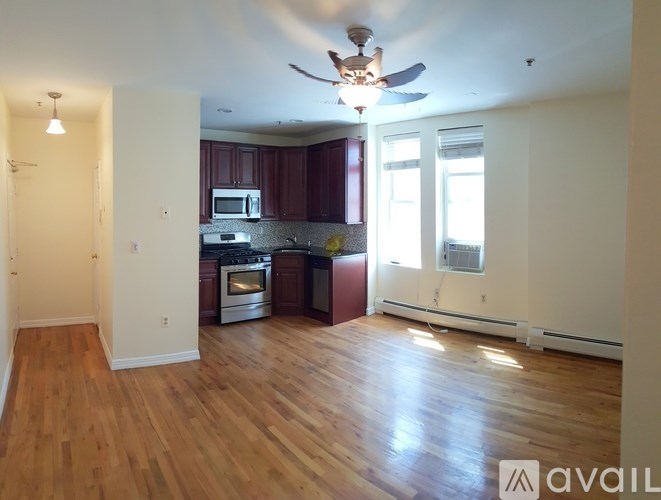 A living room with a kitchen in the background and hardwood floors.