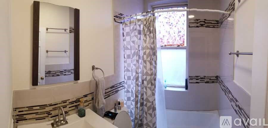 A bathroom with a sink, mirror, and shower.