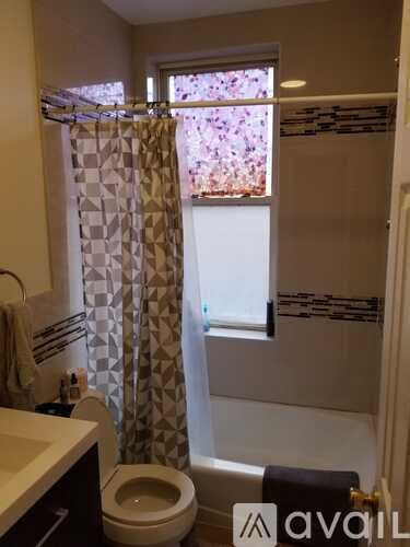 A bathroom with a toilet, sink, and shower curtain.
