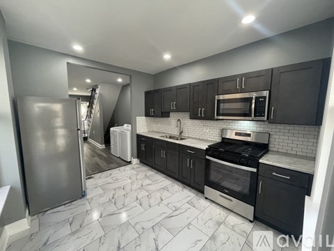 A modern kitchen with black cabinets and a marble floor.