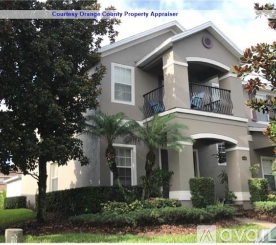 A two-story house with a balcony and a tree in front.