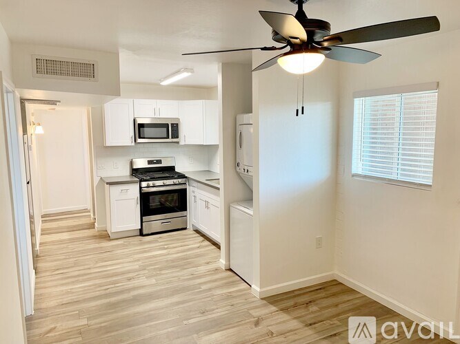 A kitchen with white cabinets and a wood floor.