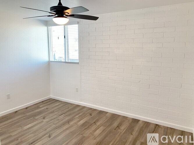 A room with a ceiling fan and a window with blinds.