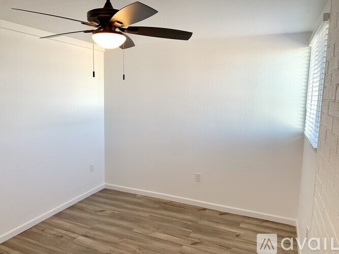 A room with a ceiling fan and wooden flooring.