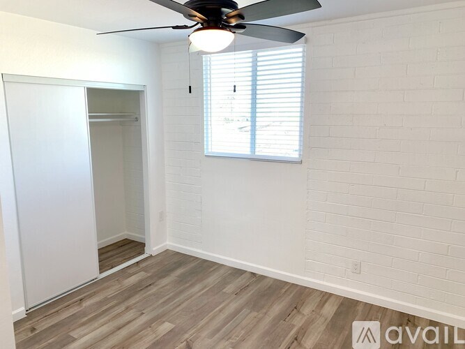 A room with a ceiling fan and a window with blinds.