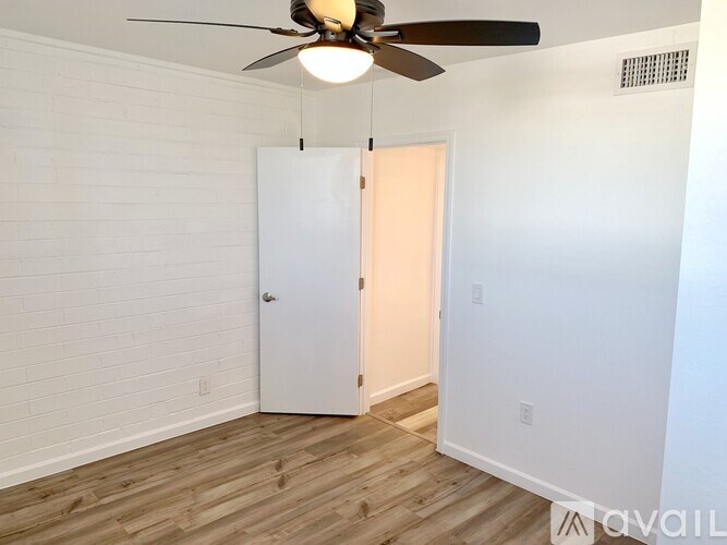 A room with a ceiling fan and a white door.