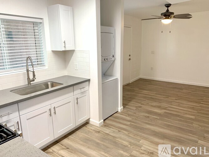A kitchen with white cabinets and a wooden floor.