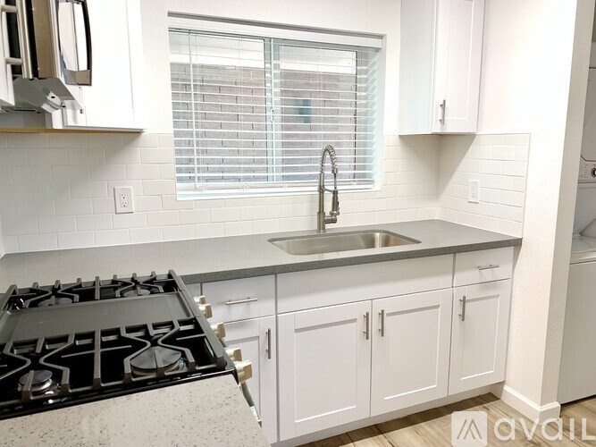 A kitchen with white cabinets and a black stove top.