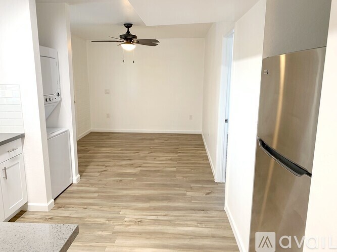 A kitchen with a stainless steel refrigerator and wooden flooring.