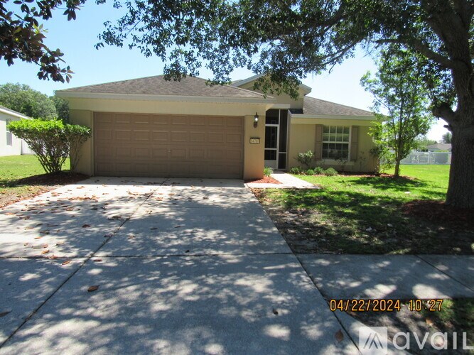 A house with a garage and a tree in front of it.