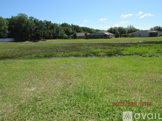 A grassy field with a few buildings in the distance and a date stamp in the corner.