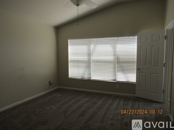 A room with a fan, window, and wooden floor.