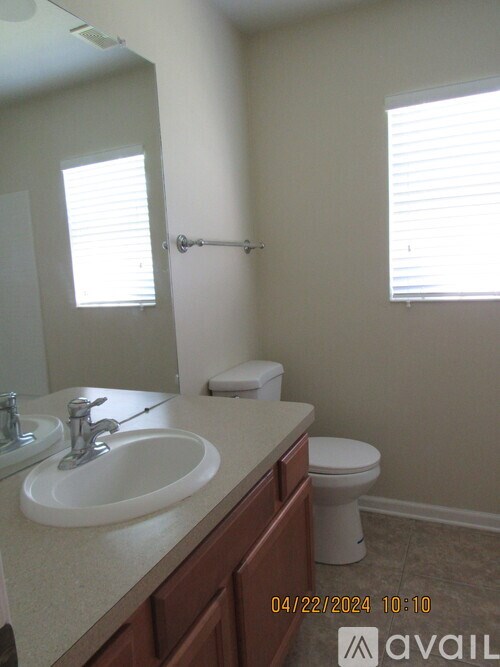 A bathroom with a toilet, sink, and mirror.