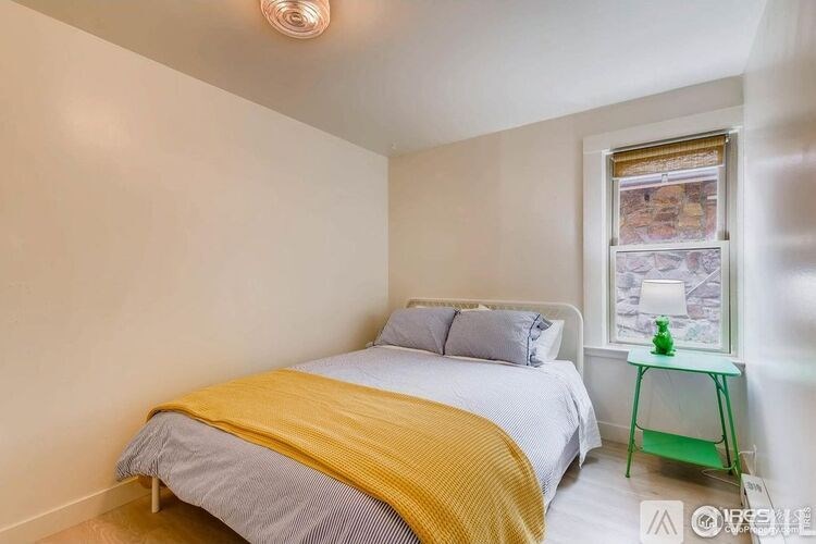 A bedroom with a bed, a nightstand, and a window.