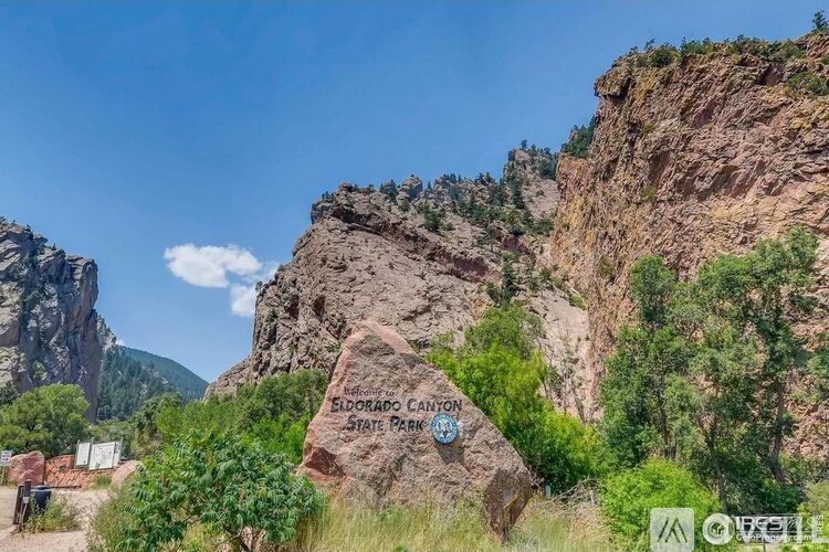 A sign for El Dorado Canyon State Park is in front of a rocky cliff.
