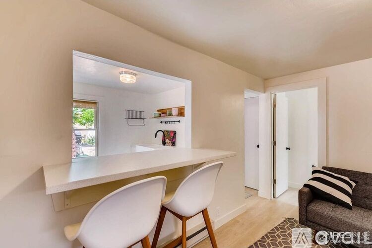 A white dining table with two chairs and a couch in a room.