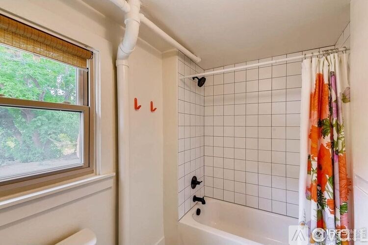 A white bathroom with a tub, shower, and a window.