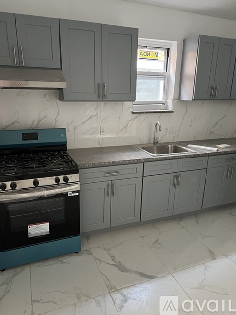 A kitchen with a stove, sink, and cabinets.