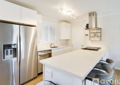 A modern kitchen with a stainless steel refrigerator and white countertops.