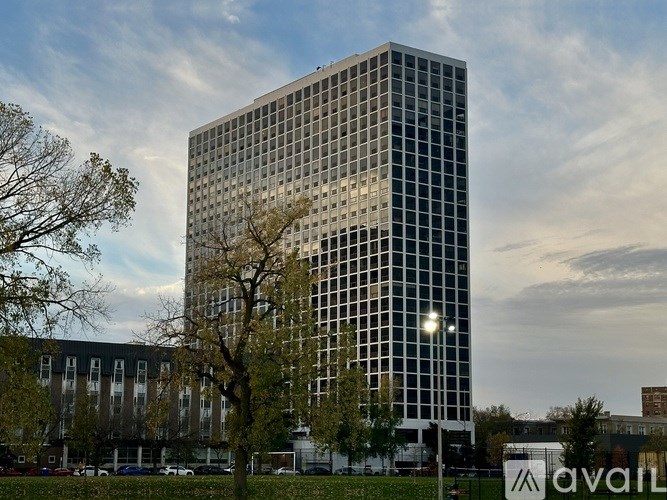 A tall glass building with a tree in front of it and the word "avail" on a sign in the foreground.