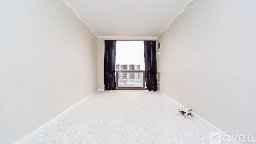 A room with a carpeted floor and a window with curtains.