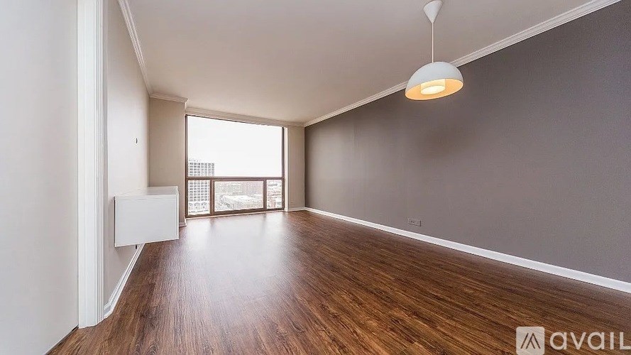 A spacious room with wooden floors and a large window.