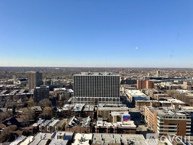 A cityscape with a large building in the center and a clear blue sky above.