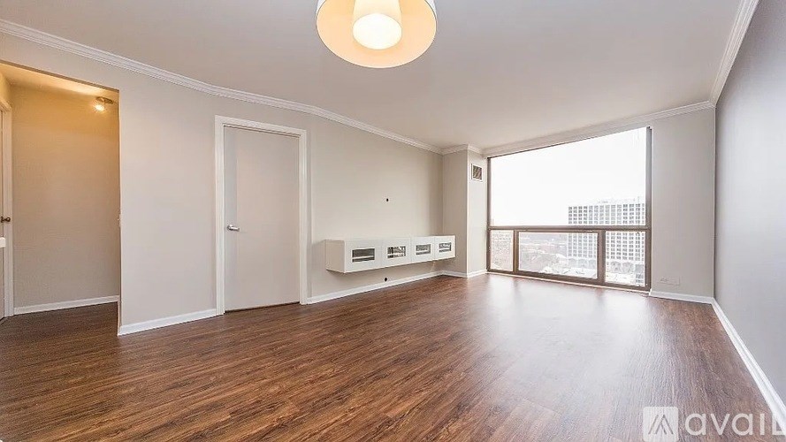 A spacious room with wooden floors and a large window.