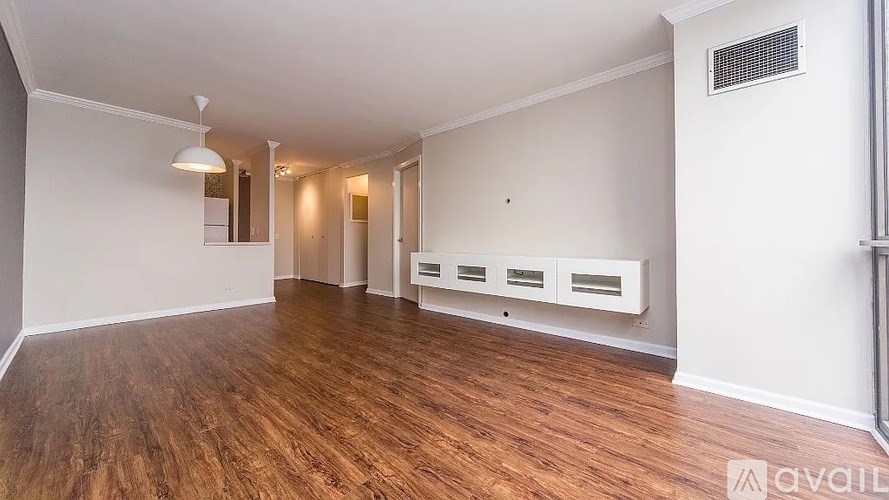 A spacious room with wooden flooring and white walls.