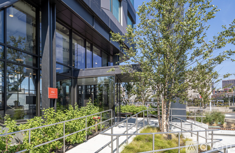 A modern building with a glass facade and a red sign on the door.
