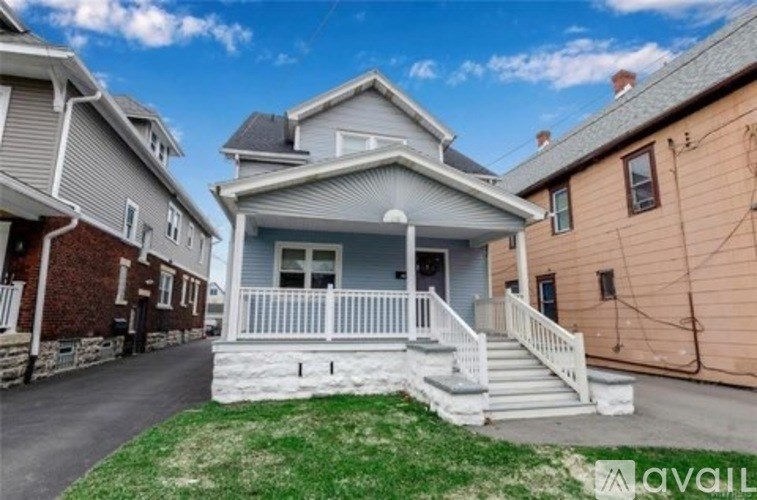 A house with a white porch and a grey roof is for sale.
