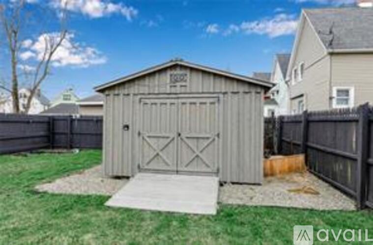 A shed with a grey roof and a grey door is situated in a yard.