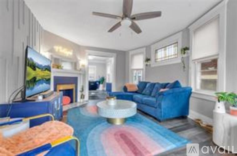 A living room with a blue couch and a television on the wall.