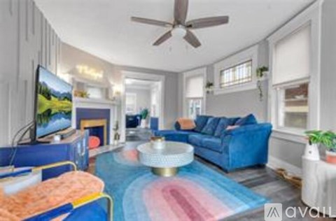 A living room with a blue couch and a television on the wall.