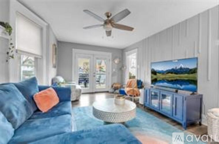 A living room with a blue couch and a ceiling fan.