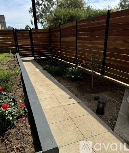 A garden with a wooden fence and a tiled walkway.